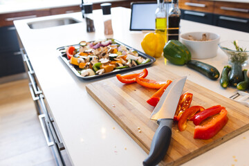 A kitchen counter displays chopped vegetables and a knife on a cutting board