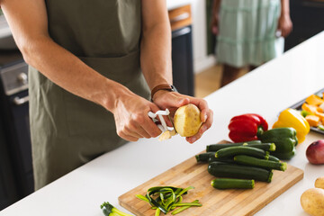 Young Caucasian man peels a potato in a modern kitchen