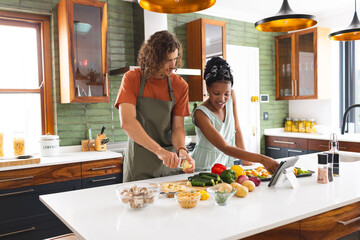 Diverse couple, young Caucasian man and African American girl cooking together in a modern kitchen - Powered by Adobe