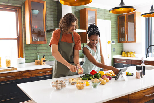 Diverse couple, young Caucasian man and African American girl cooking together in a modern kitchen