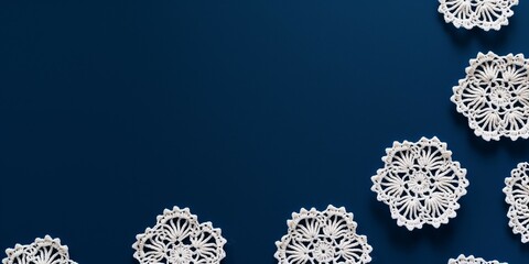 White crochet doilies on a blue background with copy space. - obrazy, fototapety, plakaty
