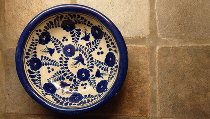 vintage, hand painted, Talavera pottery plate from Puebla, Mexico on a rustic porcelain tiled countertop - closeup