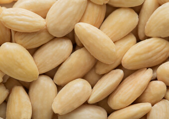 Healthy blanched almonds nuts top view macro background texture.