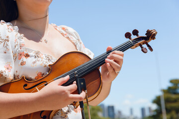 closeup of unrecognizable young female violinist on street with her violin playing strings