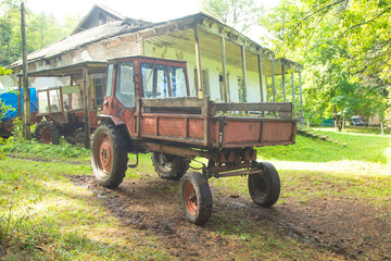 Old abandoned tractor in green forest.