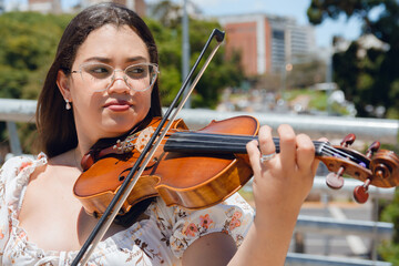 portrait of young latin woman violinist making music on street