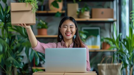 Startup SME small business entrepreneur of freelance Asian woman using a laptop with box Cheerful success Asian woman her hand lifts up online marketing packaging box and delivery SME idea