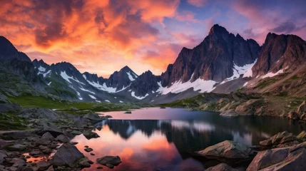 Fotobehang A spectacular landscape of a ridge, a rocky mountainside with snow and reflection in a lake at sunset with peach pink clouds. A horizontal Natural banner. © liliyabatyrova