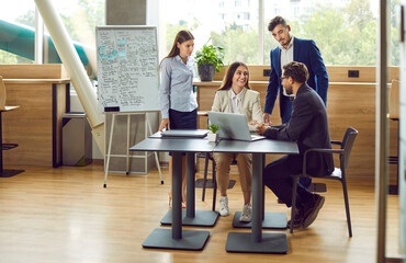 Corporate business team working on collaborative project, discussing ideas and using laptop. Group...