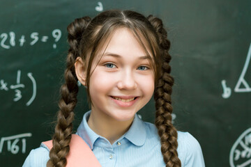 Teenage Girl with School Bag Standing at the Blackboard. Portrait schoolgirl 10 - 12 years old.