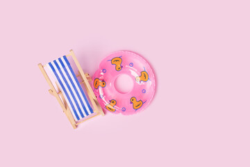 Deckchair and rubber ring, sunbathing on vacation, seaside relaxation,pink background