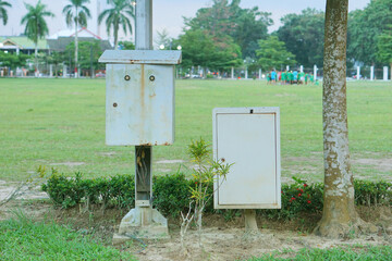 two white electrical panel boxes in a city park     