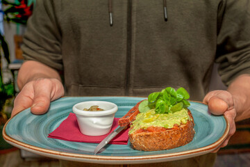 Toast with guacamole in a men,s hand, breakfast