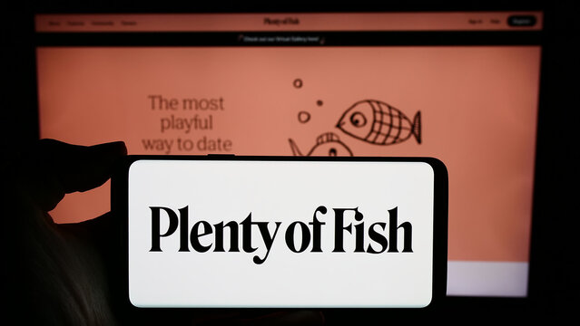 Stuttgart, Germany - 02-26-2024: Person holding smartphone with logo of Canadian online dating company Plentyoffish Media ULC in front of website. Focus on phone display.