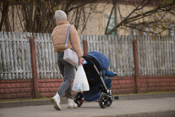 
a woman carries bags and pulls a stroller with a child