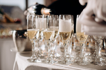 The waiter fills the glass with champagne. Catering, welcome drink, service, alcohol. A solemn event