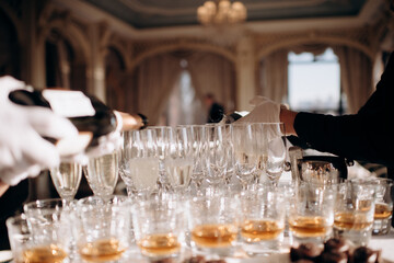 The waiter fills the glass with champagne. Catering, welcome drink, service, alcohol. A solemn event