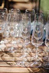 Many empty champagne or wine glasses sparkle in the sun. Preparation for a reception or holiday, a container for alcoholic beverages. Restaurant, catering, service