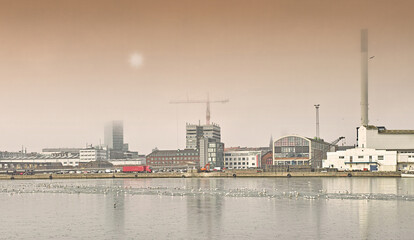 Harbor, industrial buildings and town in outdoors, treatment plant and development by factory. Production, warehouse and power station or refinery in Aarhaus, Denmark and river or lake outside