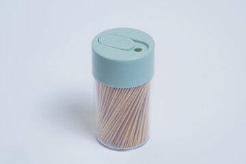 a collection of toothpicks in a cylindrical plastic container on a white background