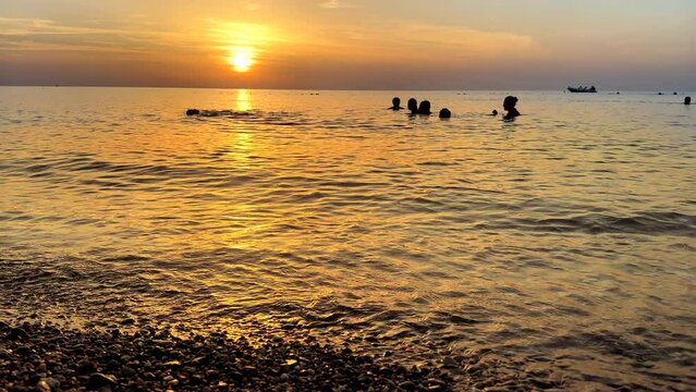 People enjoy summer beach holiday during orange color sunset