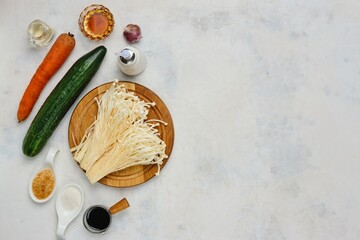 Prepared ingredients for cooking salad with enoki mushrooms., Golden threads on a light concrete...