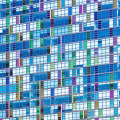 A wall of many windows and reflections, looking up at the exterior of contemporary architecture. Colourful blue tones. Architectural abstract background.