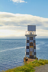 Lighthouse, ocean and blue sky by beach in nature for holiday, vacation or travel destination....