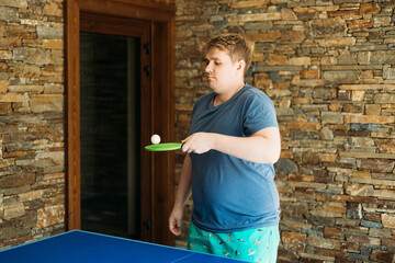 Young man playing ping pong. He holds a racket in his hands. Table tennis. The concept of sport and...