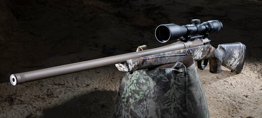 Hunting rifle and rifle scope just before dawn on a camo shooting bag just before dawn.