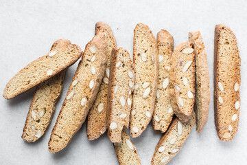 almond biscotti on white parchment lined tray, almond cantucci cookies on a white board, flatlay of slices of biscotti cookies or twice baked cookies