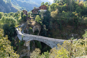 Fototapeta premium High angle view of the 1545 build semi-circular masonry pedestrian arch Chi Bridge (Chibrigga) in Stalden, Switzerland crossing a gorge in the Valais region