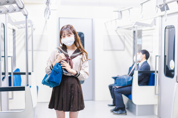 マスクをして電車通学をする女子高生