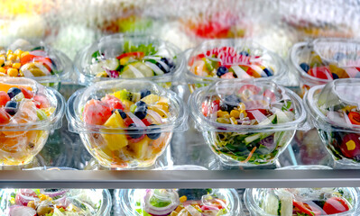 Boxes with fruit and vegetable salads in a commercial fridge