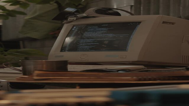 Vertical shot of old computer with code on display at desk post apocalypse shelter with no people
