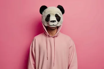 Fototapeten Expressive man wearing a panda mask on top of his head against a pink wall. © Joaquin Corbalan
