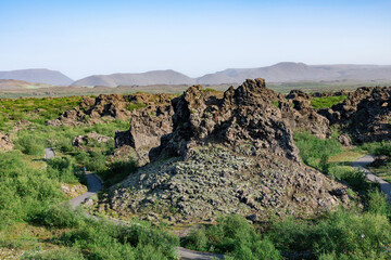 Obraz premium Panoramic view over the unusually shaped lava fields and rock formations of Dimmuborgir near Lake Myvatn, Icelandare which are badlands of lava pillars, caves, rugged crags and towering rocks