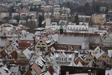 A picturesque snow-covered european city with glistening white rooftops, frosty streets, and snow-capped mountains in the distance.
