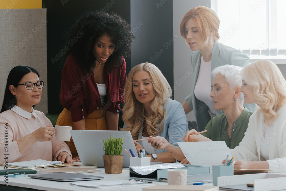 Sticker Group of mature women using laptop while discussing business in the office together