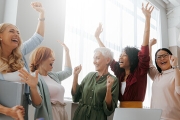 Group of happy businesswomen gesturing and smiling while having meeting in office - 749389327