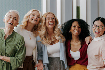 Group of happy mature women looking at camera while standing in the office together