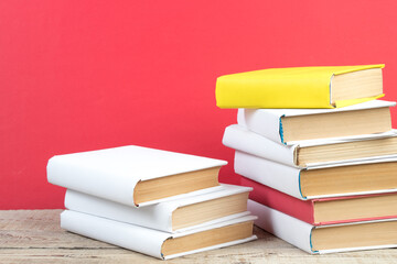 Books stacking. Books on wooden table and red background. Back to school. Copy space for ad text.