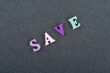 SAVE word on black board background composed from colorful abc alphabet block wooden letters, copy space for ad text. Learning english concept.