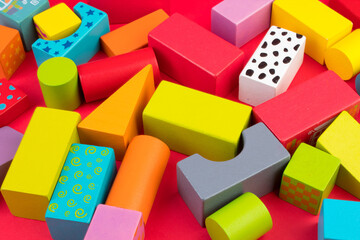 Top view of colorful wooden bricks on the table. Early learning. Educational toys on a red background.