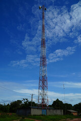Red and white cell phone mast, radio communication station against bright blue sky. Itacoatiara, Amazonas state, Brazil.