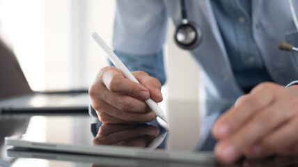 Doctor using stylus pen writing prescription for patient on digital tablet computer, electronic health record, medical insurance, health technology, close up