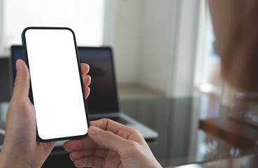 Cell phone blank screen mockup. Woman hand holding,  using mobile phone on desk at office.background empty space for advertise. Social media marketing, website template