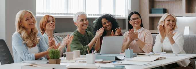 Group of happy businesswomen applauding while having meeting in the office - 749399192