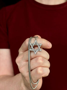 Young man's hand holding a David Star ("Magen David") key chain. The State of Israel, Judaism, Zionism concept image. Conversion to Judaism, giyur, Passover. 