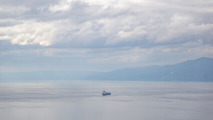 View of the croatian coast of Rijeka on a stormy day with a big ship in the middle of the sea